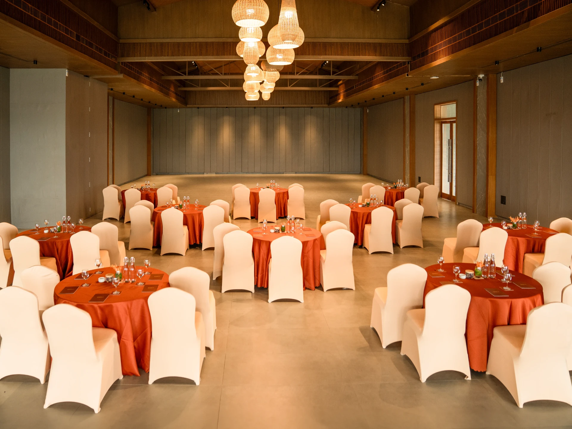 An ARTH gathering space set with round tables beneath woven pendant lights